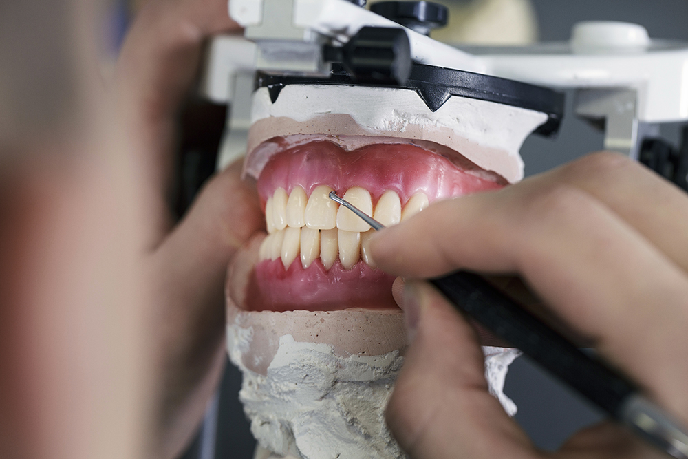 dental technician creates removable dental prostheses with pink